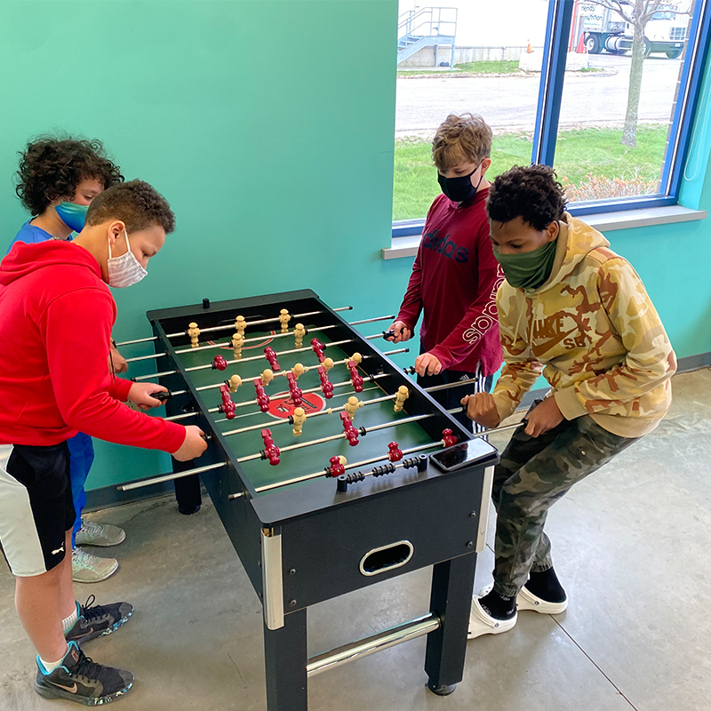 Four students playing foosball in the recreation room.